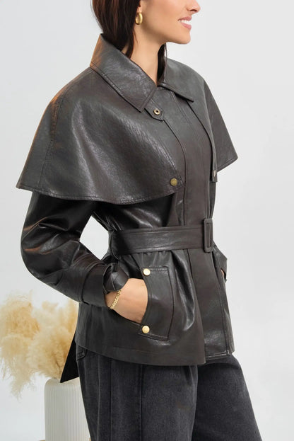 Mujer vistiendo chaqueta de cuero marrón oscuro con capa y cinturón ajustable