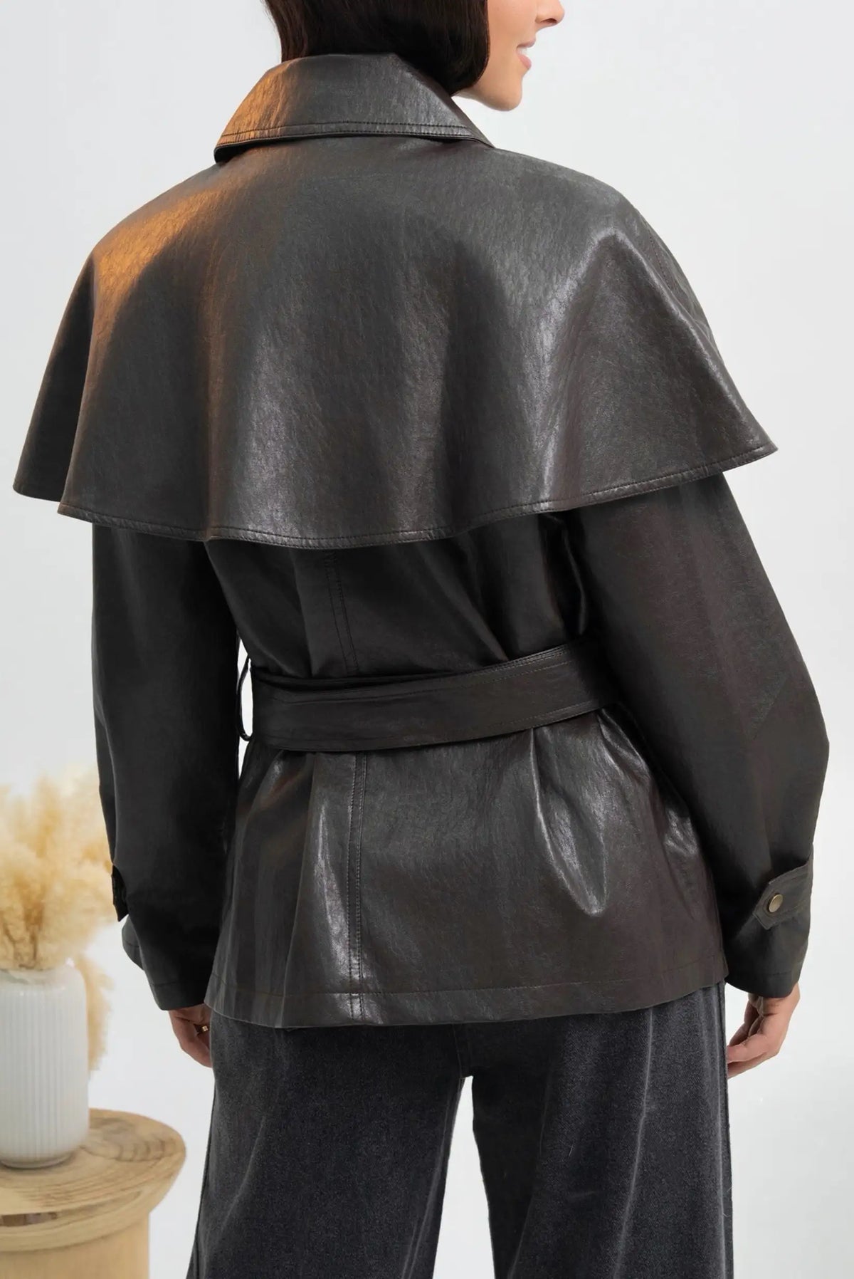 Vista trasera de chaqueta de cuero sintético marrón oscuro con capa y cinturón