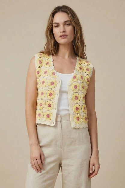 Mujer con chaleco de crochet amarillo y flores, look casual primaveral, fondo beige