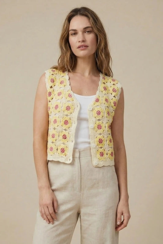 Mujer con chaleco de crochet amarillo y flores, look casual primaveral, fondo beige