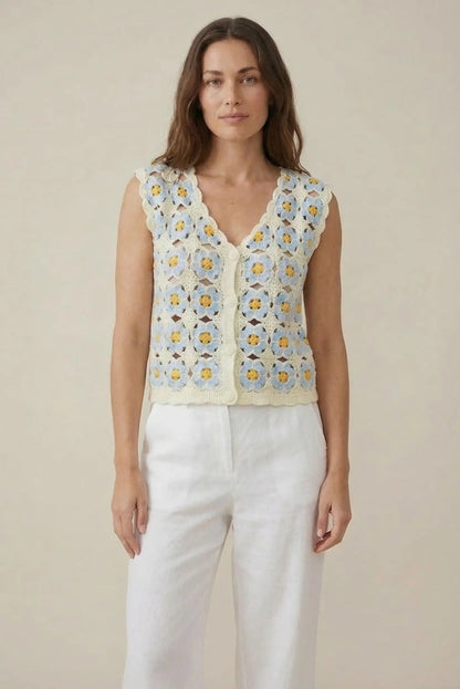 Mujer con chaleco de crochet azul claro y flores, look casual de primavera-verano