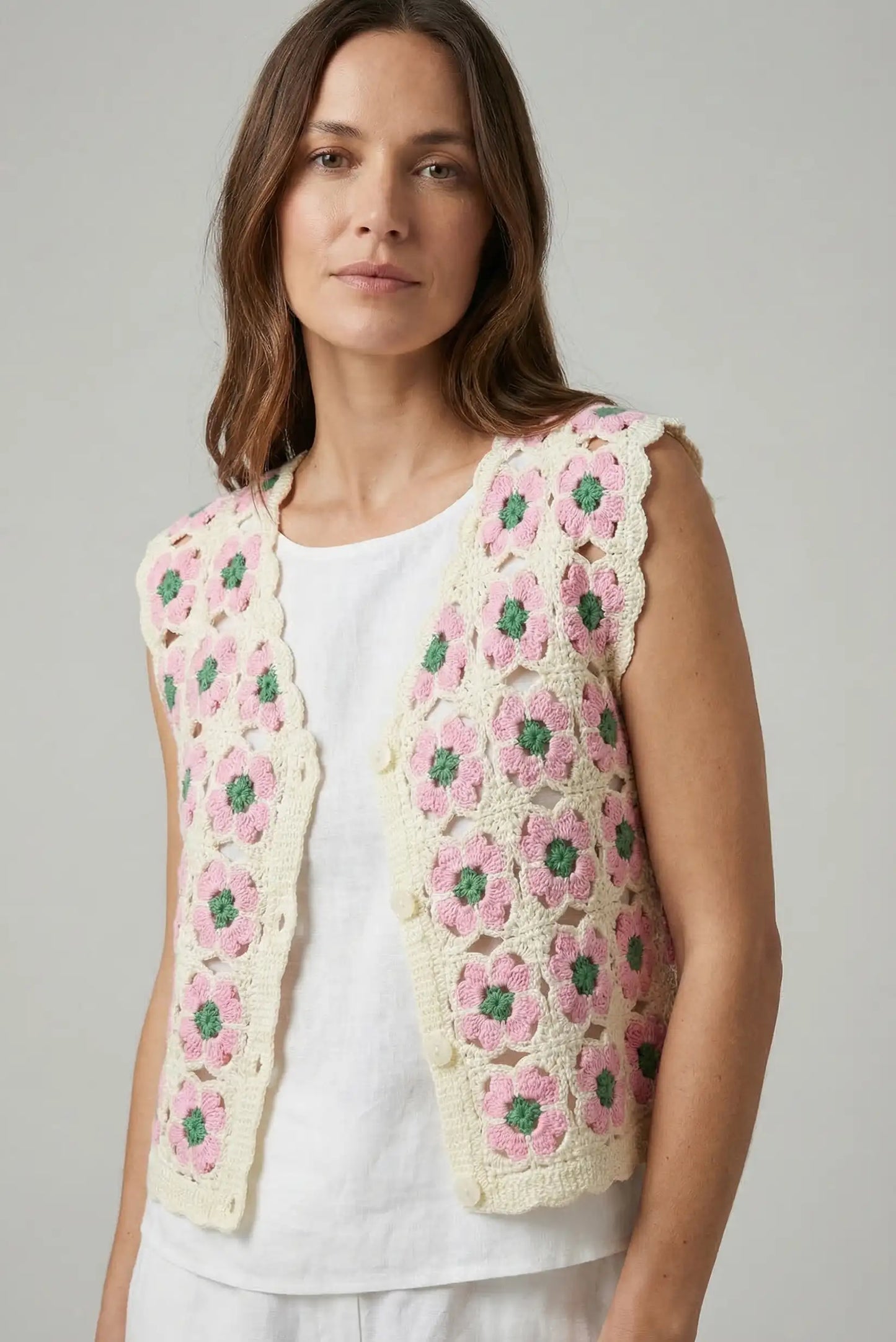 Mujer con chaleco de crochet rosa y beige con diseño floral, moda casual primavera.