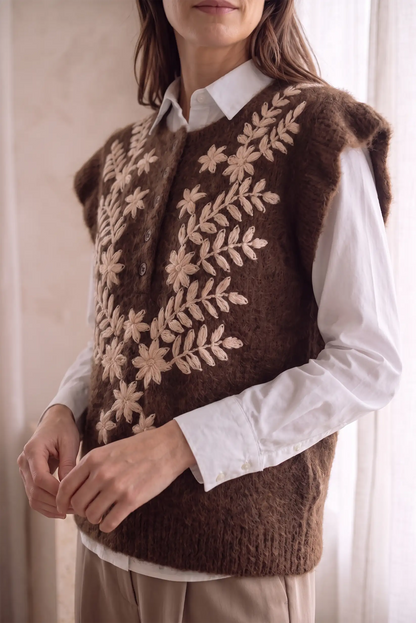 Chaleco de lana marrón con bordados florales beige sobre camisa blanca
