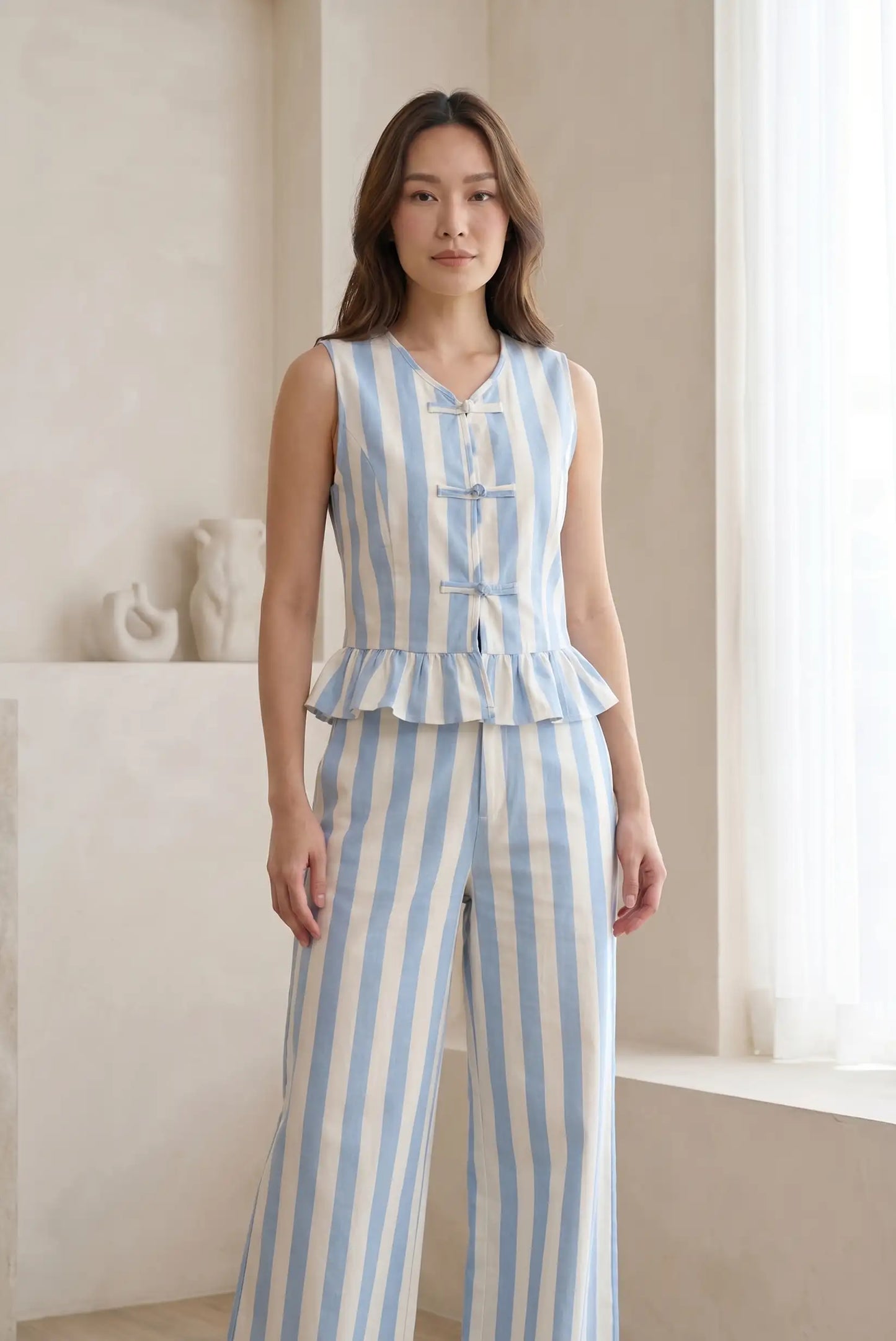 Mujer con chaleco y pantalón de rayas azul y blanco, look casual elegante femenino.
