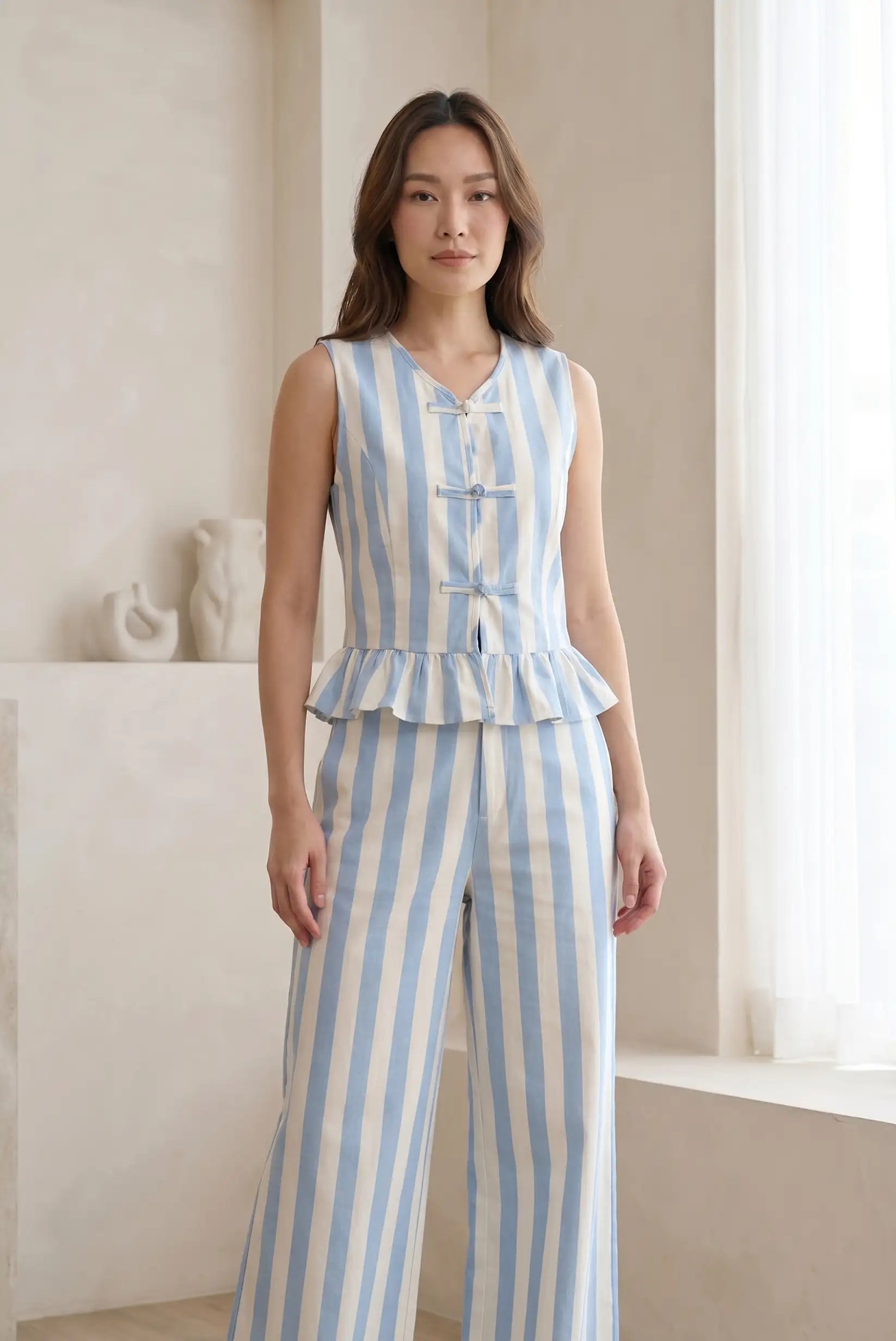Mujer con chaleco y pantalón de rayas azul y blanco, look casual elegante femenino.