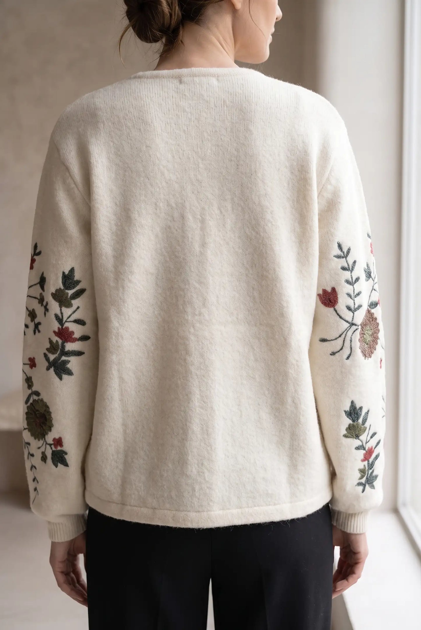 Vista trasera de jersey blanco de punto con bordados florales coloridos en las mangas