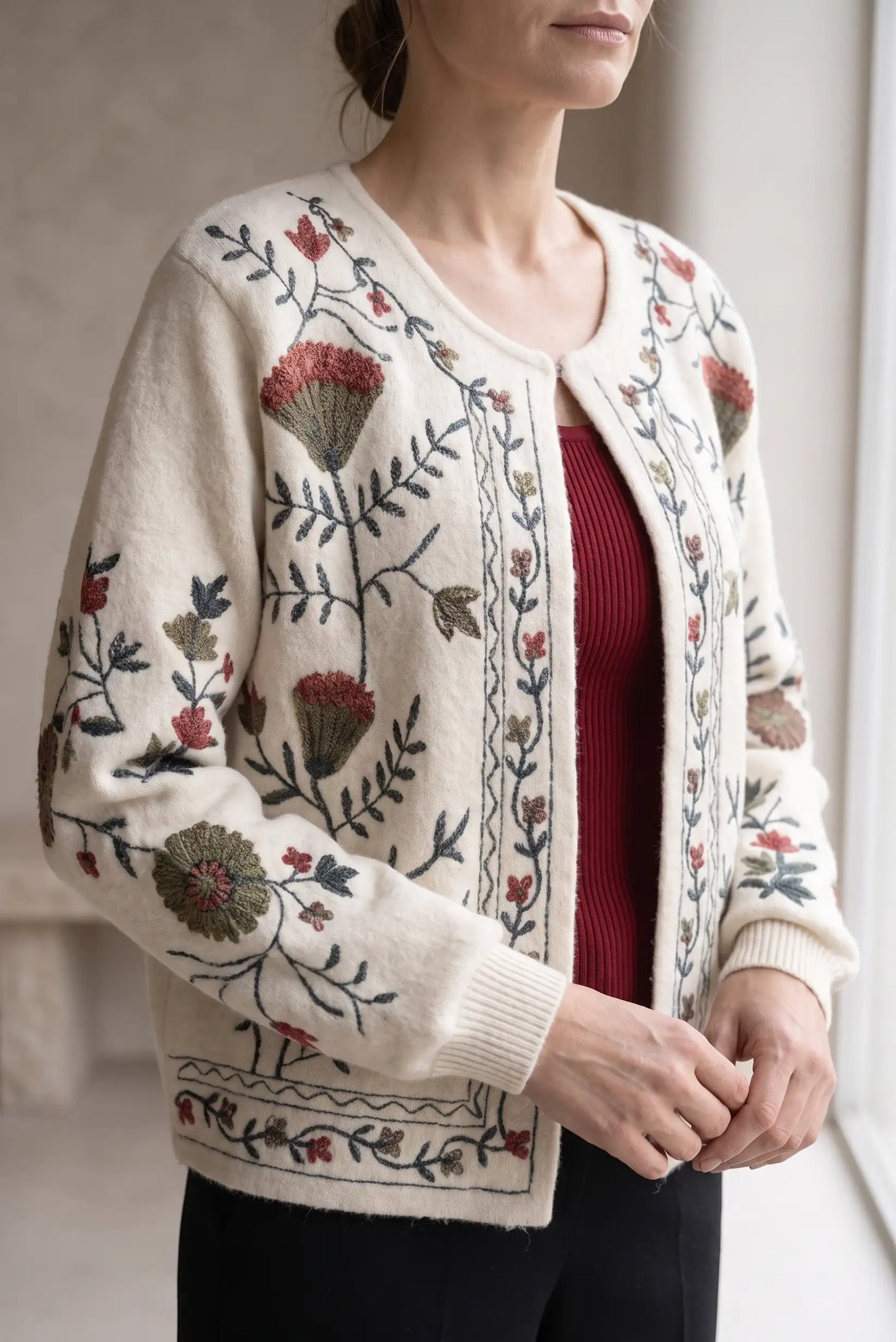 Chaqueta de punto color crema con bordados florales artesanales sobre camiseta roja