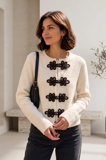 Mujer vistiendo chaqueta beige estilo Napoleón de CHICA del Sur con cierres decorativos negros.