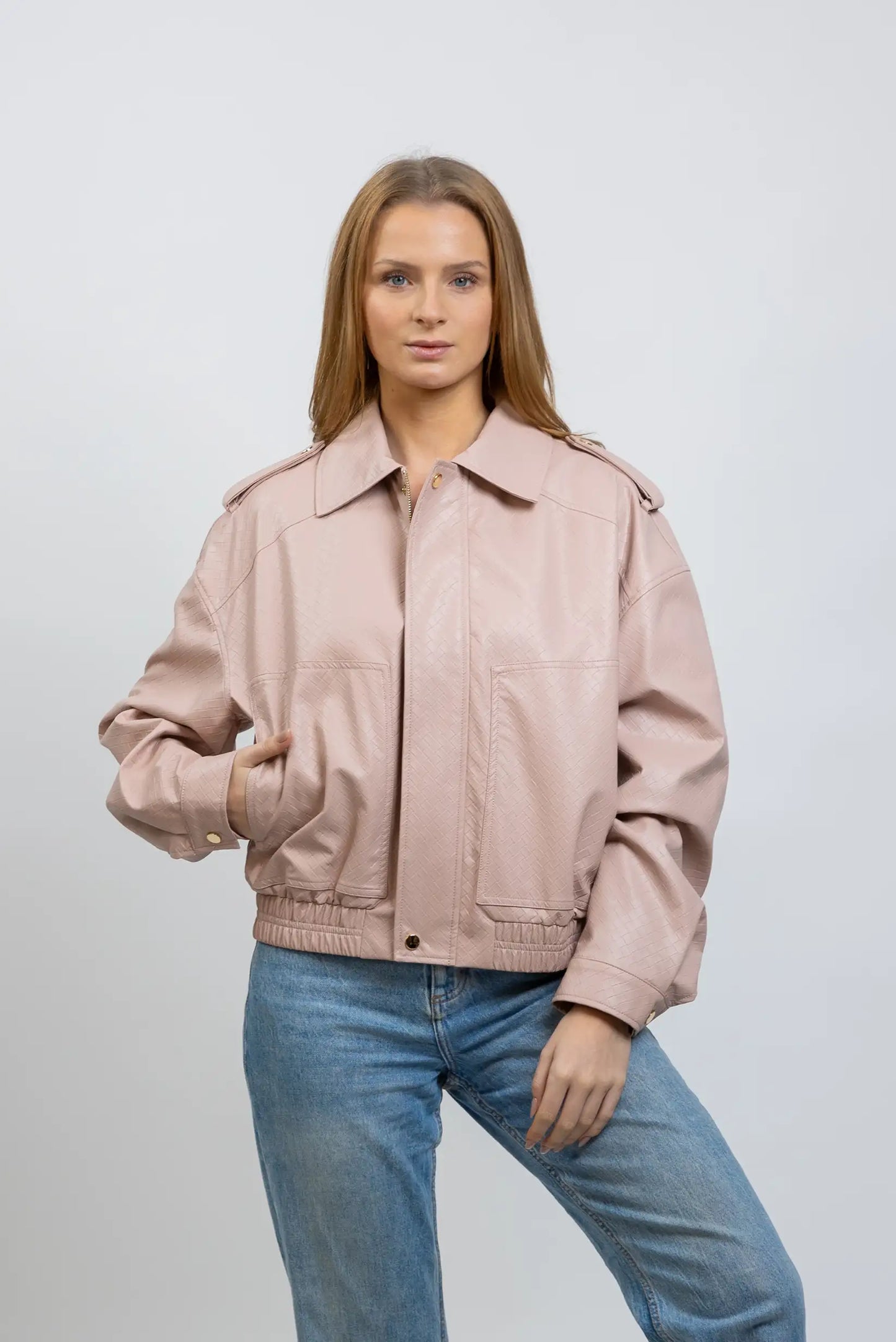 Mujer con chaqueta rosa claro de polipiel para entretiempo y jeans, estilo casual moda femenina.