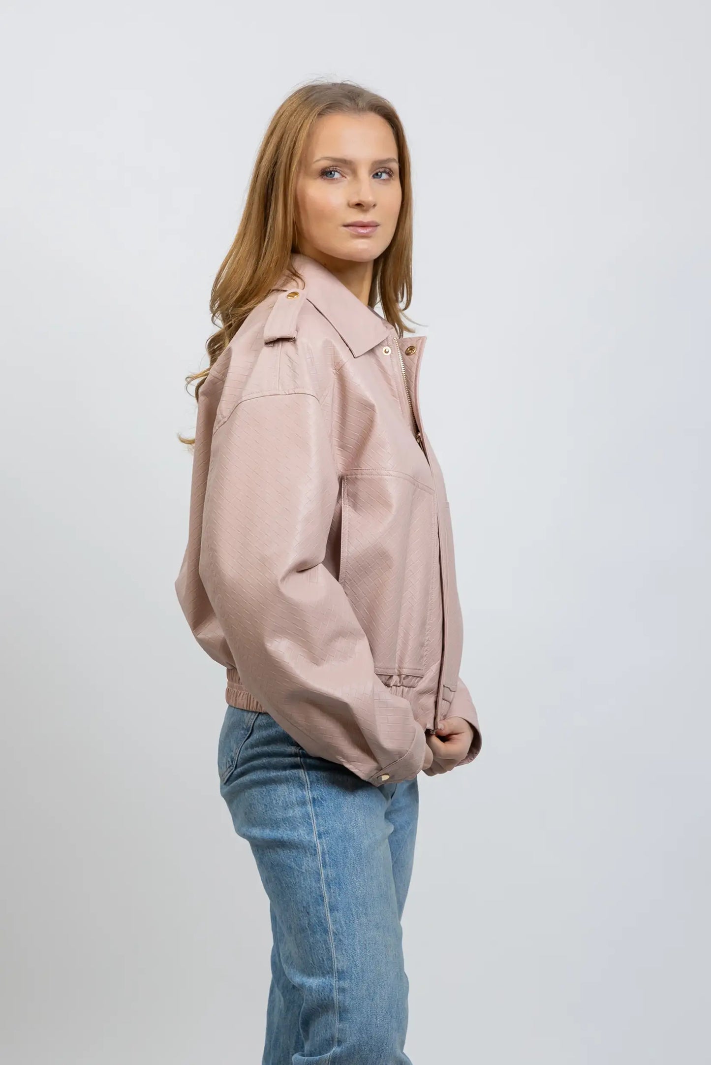 Mujer con chaqueta de polipiel rosa claro y jeans, moda casual femenina de entretiempo.