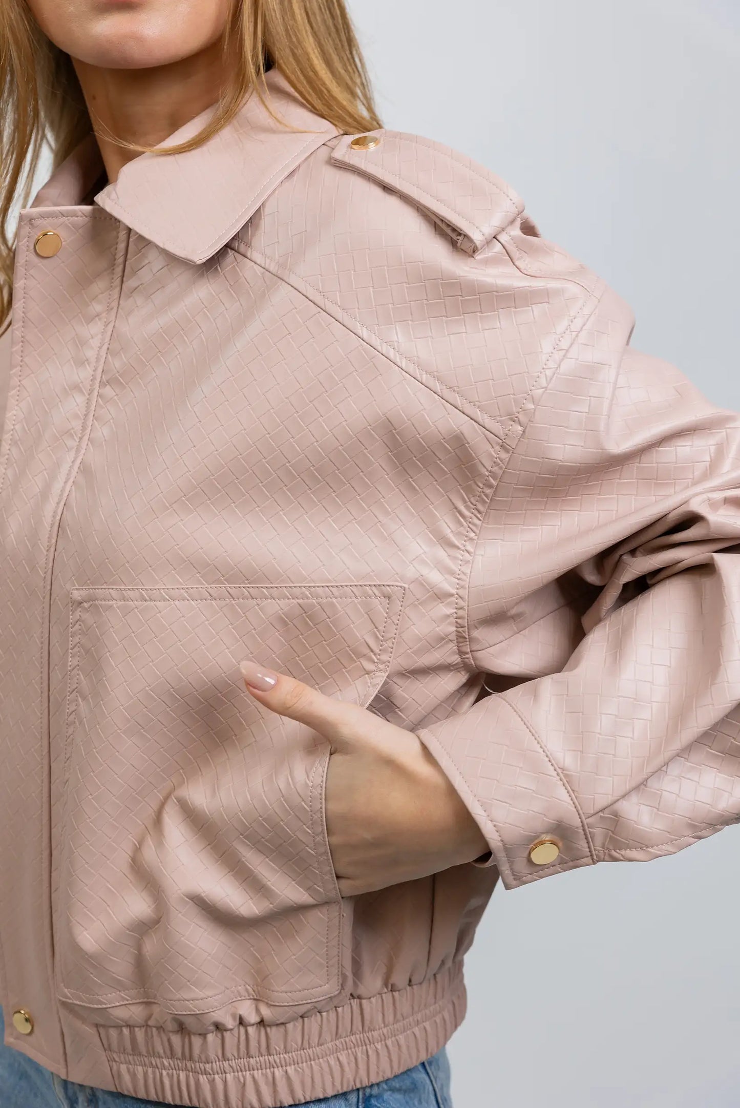 Chaqueta de mujer rosa claro en polipiel con textura y botones dorados, estilo casual.