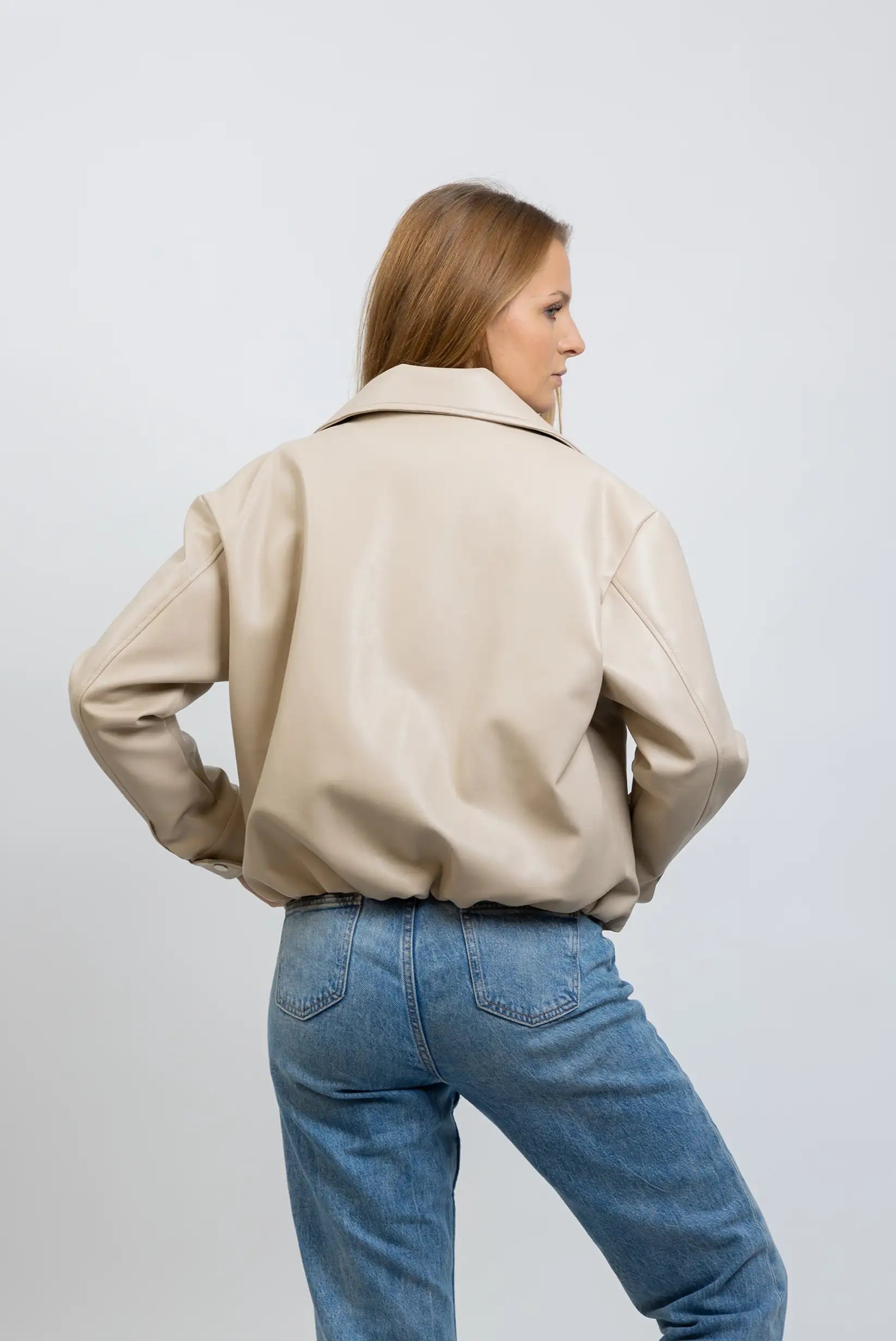 Chaqueta corta de polipiel beige para mujer, estilo casual, vista trasera, con jeans.