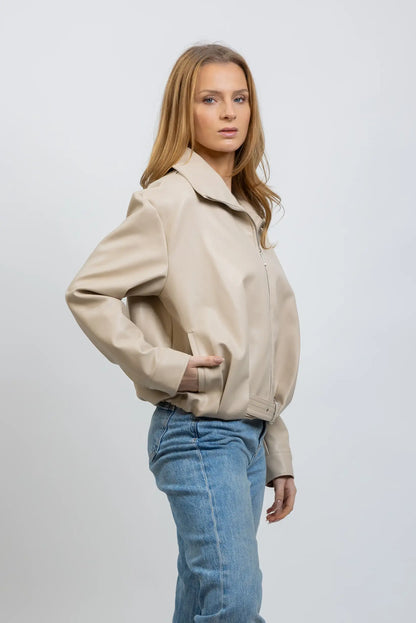 Mujer con chaqueta corta de polipiel beige y jeans, moda casual de entretiempo