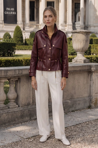 Chaqueta de cuero burdeos con botones dorados y pantalón blanco ancho, look urbano elegante para mujer
