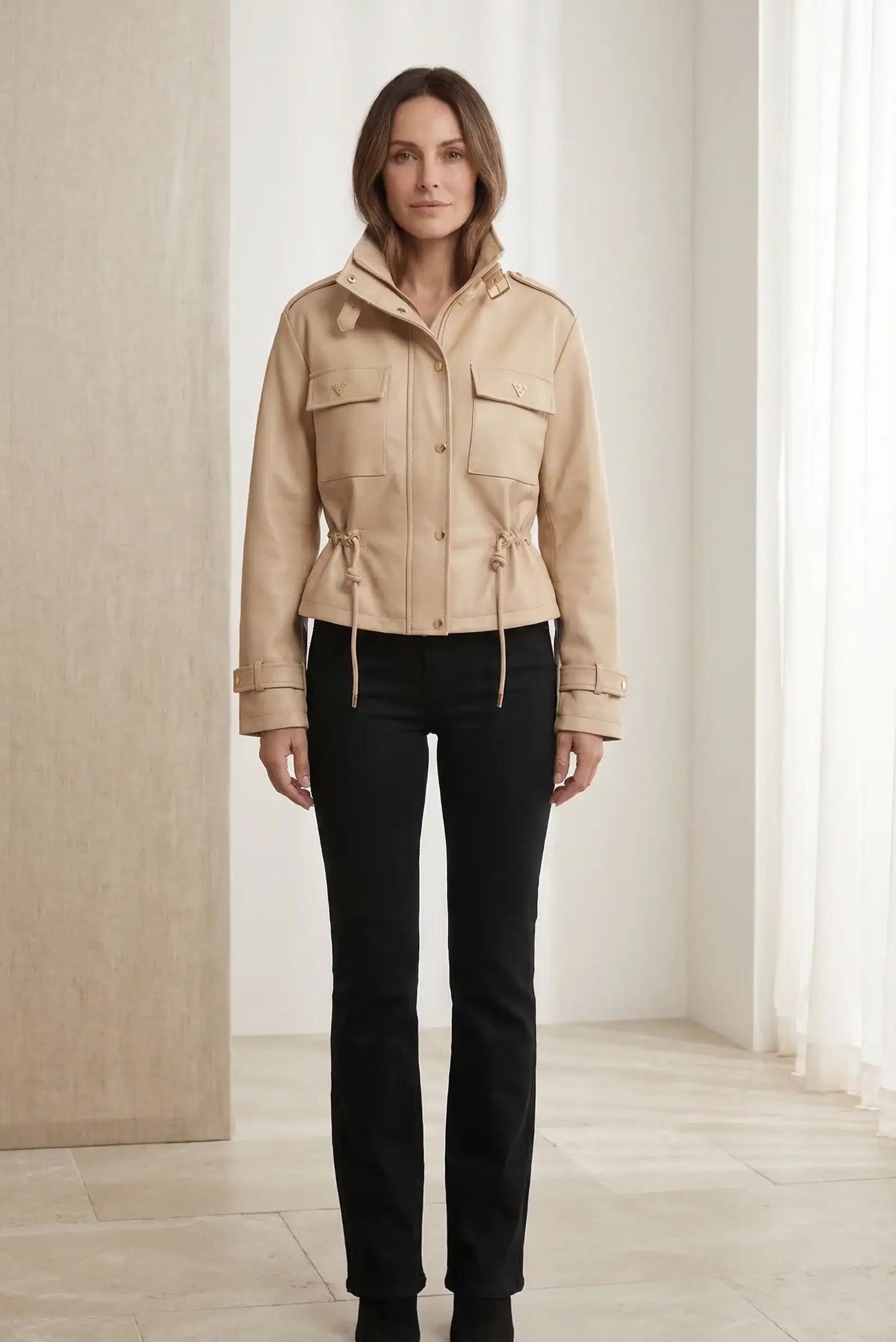 Mujer con chaqueta beige de polipiel para primavera, cuello alto y bolsillos, pantalón negro
