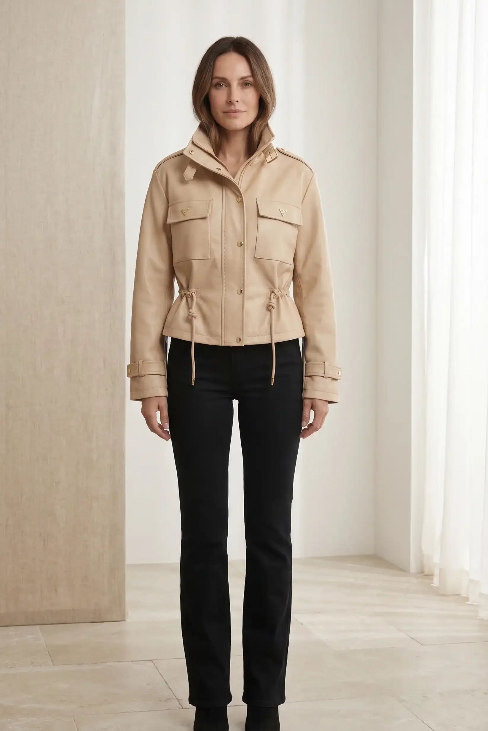 Mujer con chaqueta beige de polipiel para primavera, cuello alto y bolsillos, pantalón negro