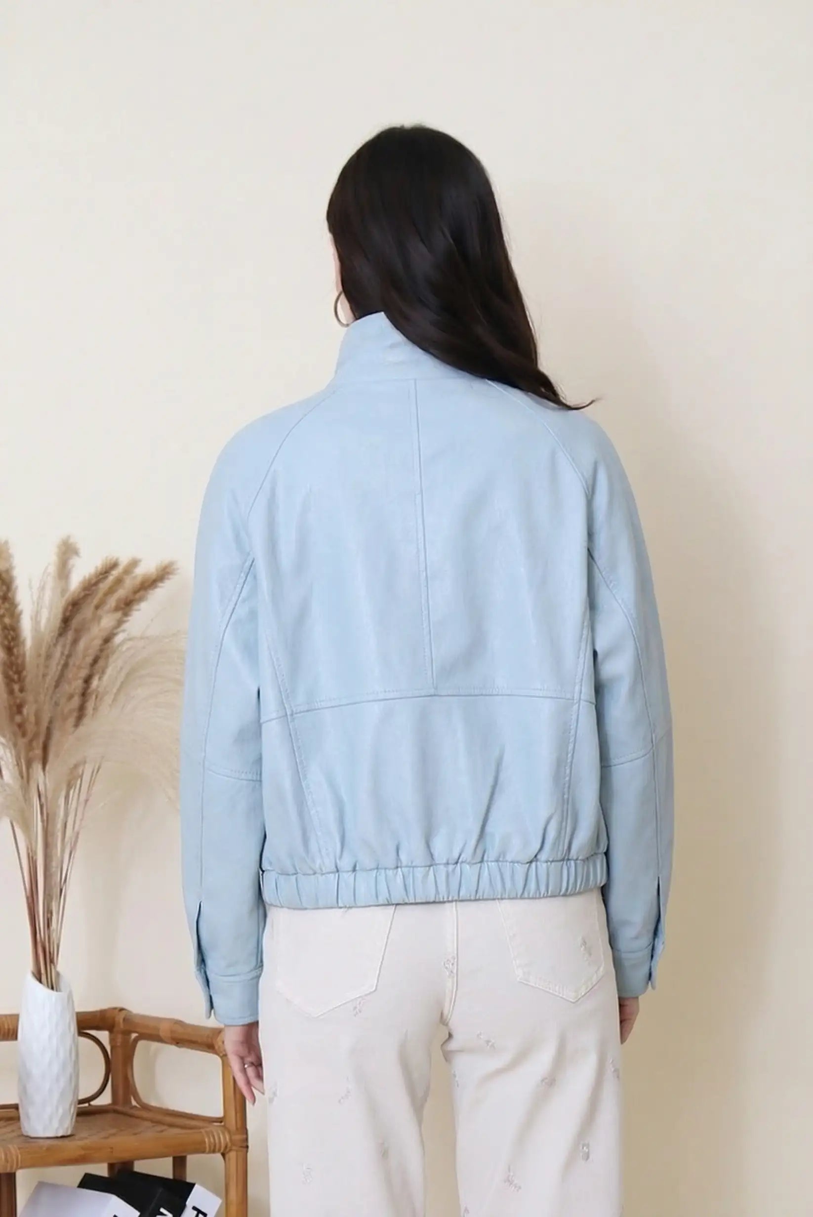 Mujer de espaldas con chaqueta azul de polipiel, look casual de primavera.