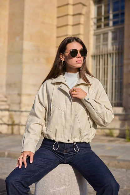 Mujer con chaqueta de polipiel beige claro y jeans oscuros, moda primavera casual