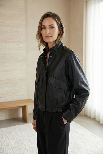 Mujer con chaqueta primavera de polipiel negro, look casual elegante en interior luminoso