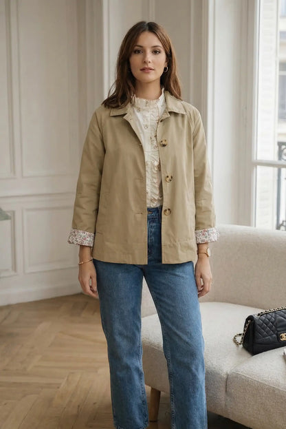 Mujer con chaqueta beige de primavera, puños con estampado floral y camisa blanca, estilo casual.