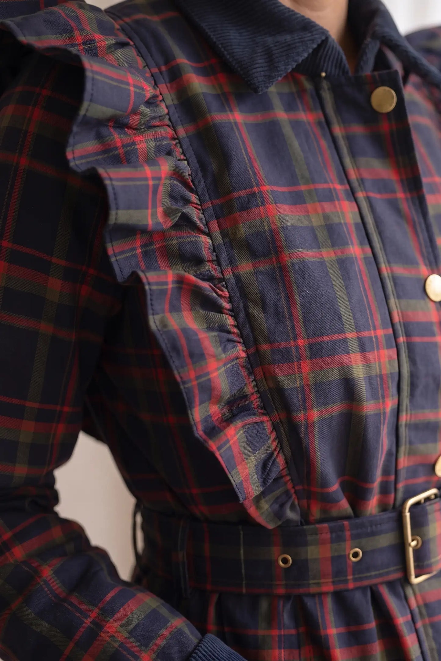 Detalle de chaqueta femenina a cuadros rojos y azules con volantes y cinturón