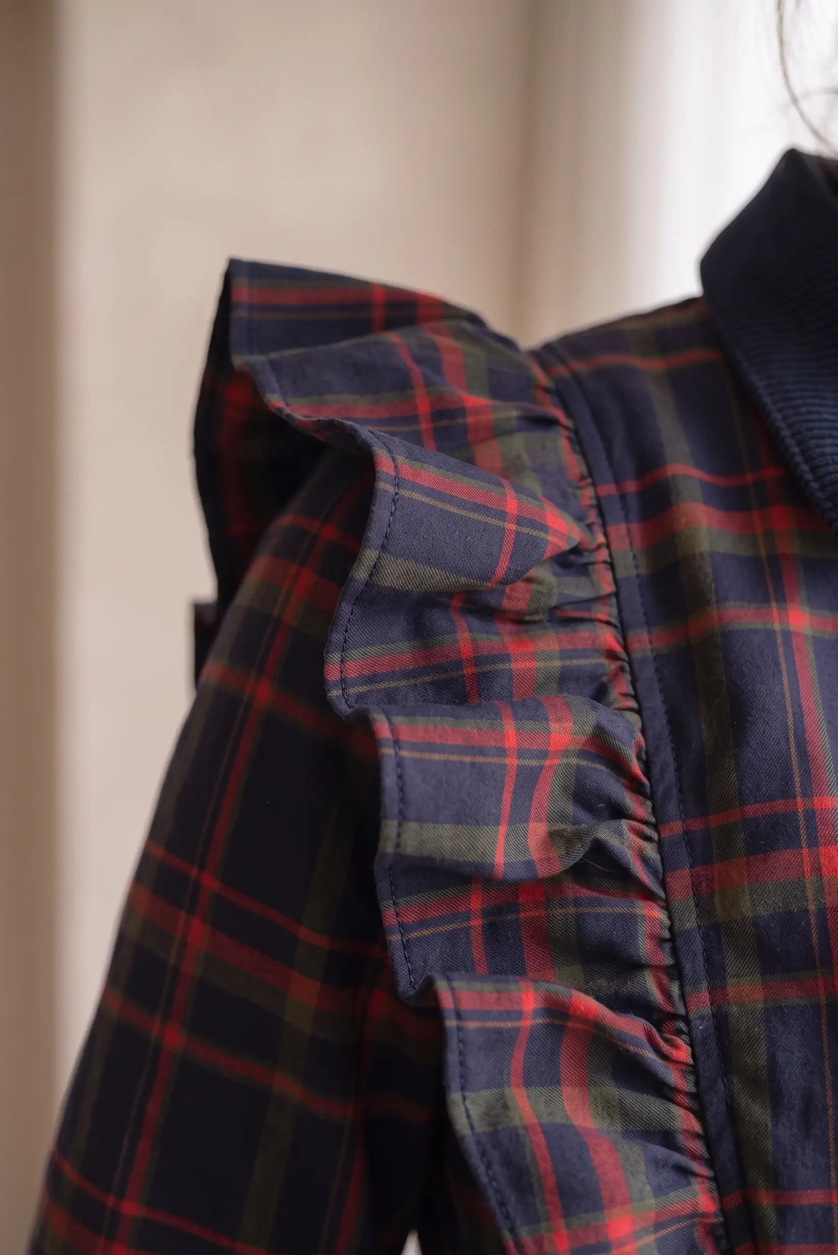 Detalle de blusa femenina a cuadros azul, rojo y verde con volante en el hombro