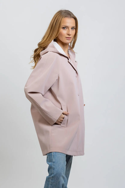 Mujer con chubasquero largo rosa empolvado, estilo casual, primavera, fondo neutro.