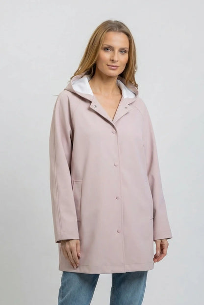 Mujer lleva chubasquero largo rosa empolvado con capucha, look casual de primavera.