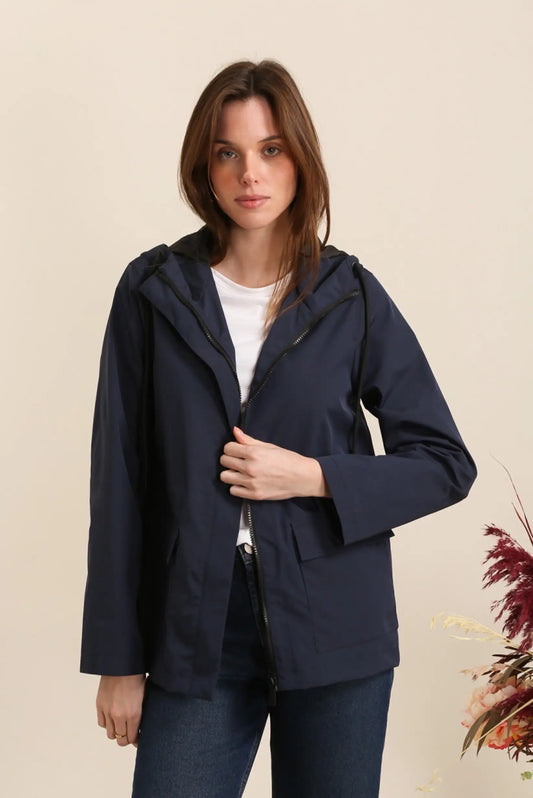 Mujer con chubasquero corto azul oscuro, look casual CHICA del Sur, fondo neutro.