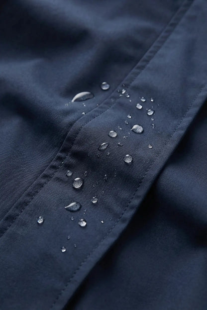 Detalle de chubasquero corto azul oscuro impermeable para mujer con gotas de agua, CHICA del Sur.