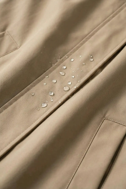 Detalle de chubasquero mujer taupe repelente al agua, gotas sobre tejido beige
