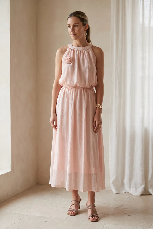 Mujer con conjunto rosa empolvado, falda larga y top con flor, moda primavera elegante