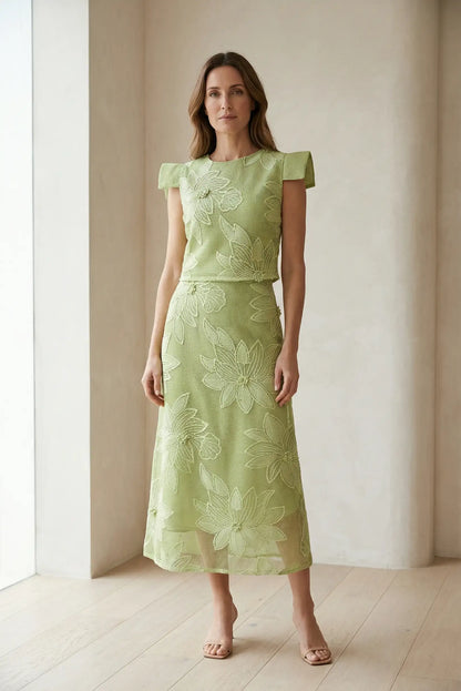 Mujer con conjunto de top y falda verde manzana, flores en relieve, estilo primavera elegante.