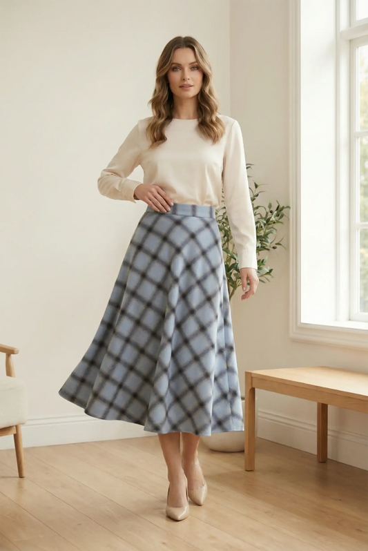 Mujer con falda larga azul de cuadros y blusa beige en interior luminoso, moda CHICA del Sur