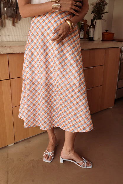 Falda larga mujer de cuadros vichy naranja y azul, look casual en cocina moderna.