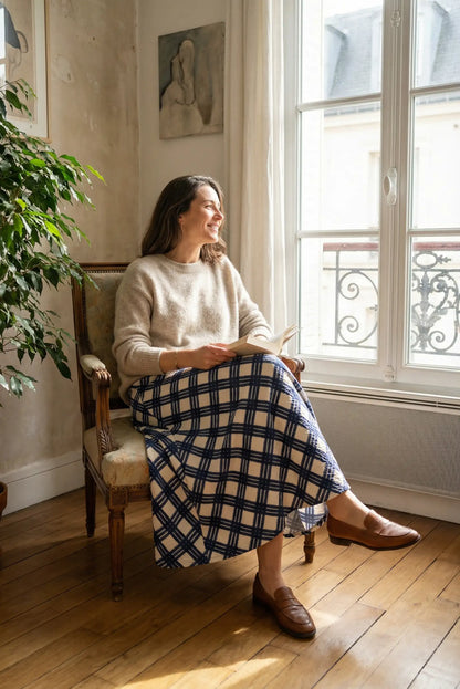 Mujer sentada con falda larga de rombos azules y suéter beige, look casual CHICA del Sur