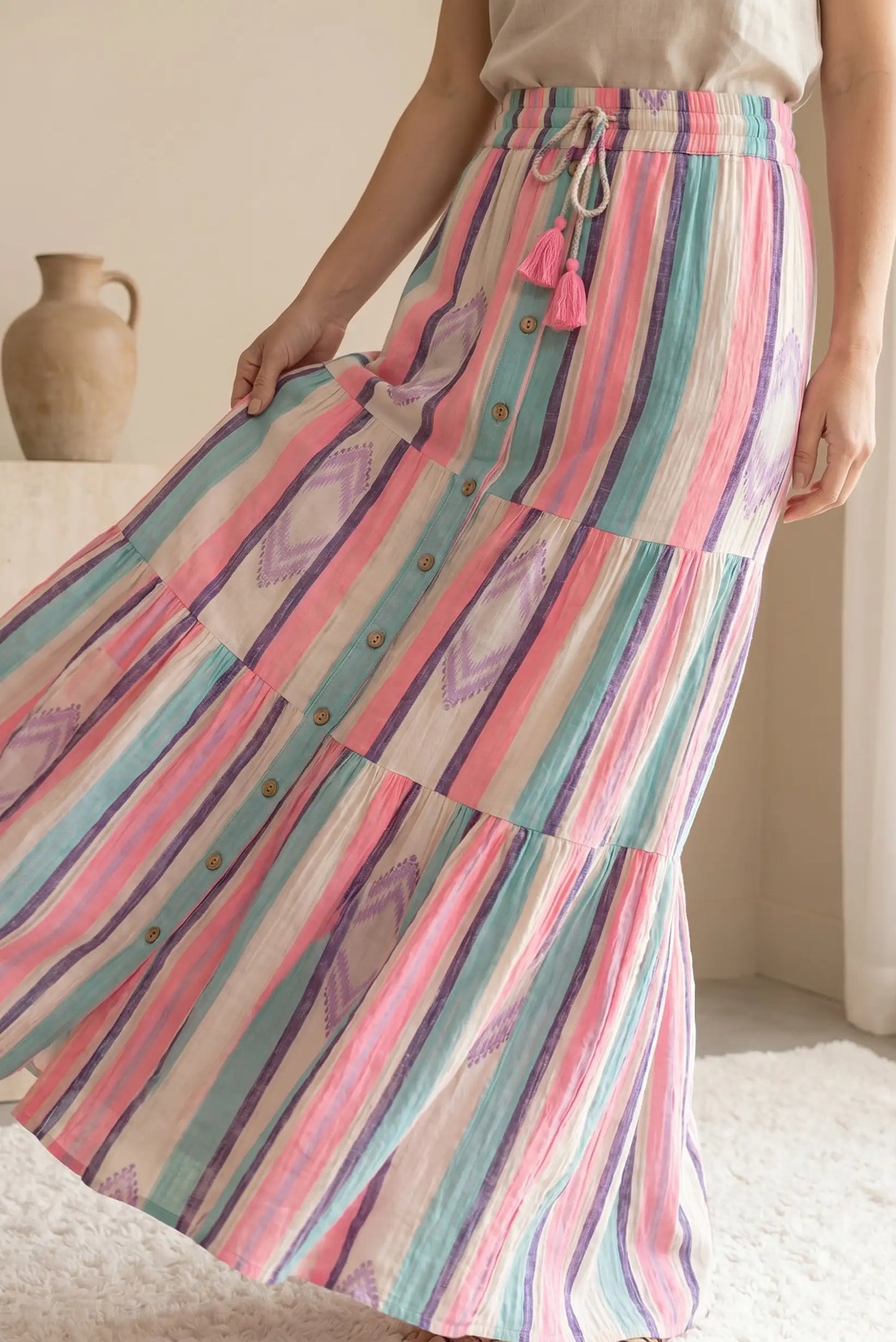 Falda larga de rayas rosas, lilas y turquesa, botones frontales y cordón con borlas, estilo primavera.