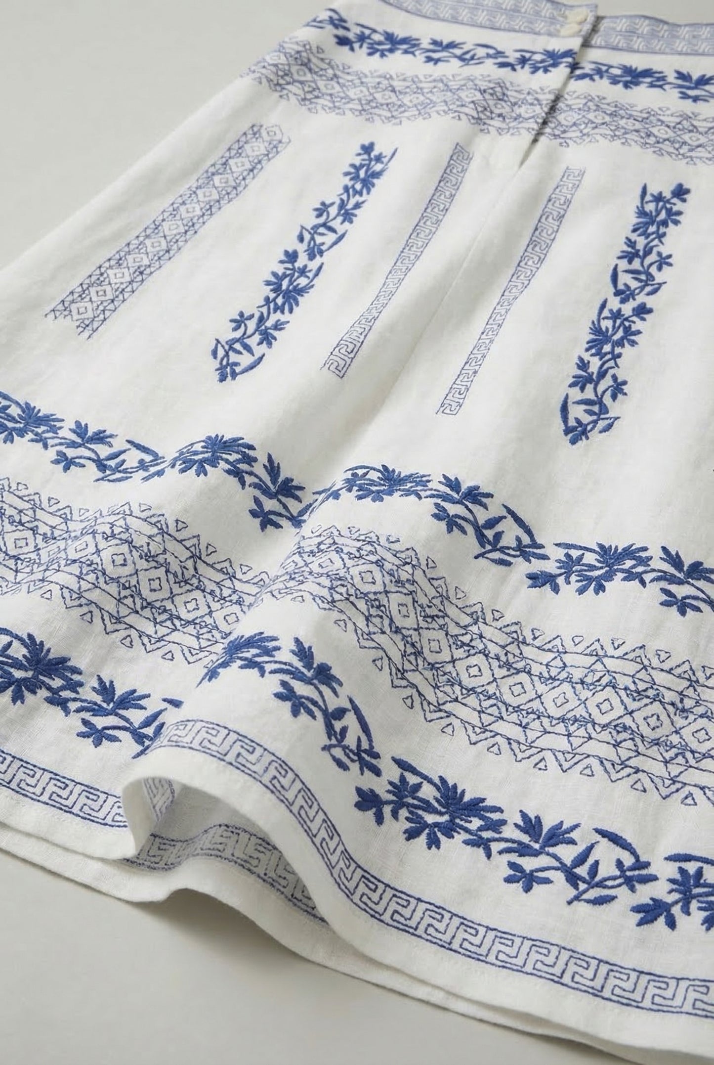 Falda blanca de mujer con bordados florales azul navy y diseño geométrico, estilo primavera.
