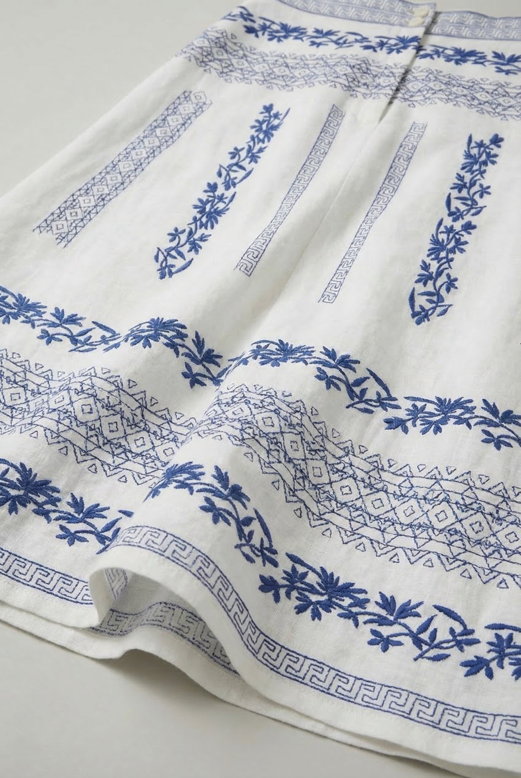 Falda blanca de mujer con bordados florales azul navy y diseño geométrico, estilo primavera.