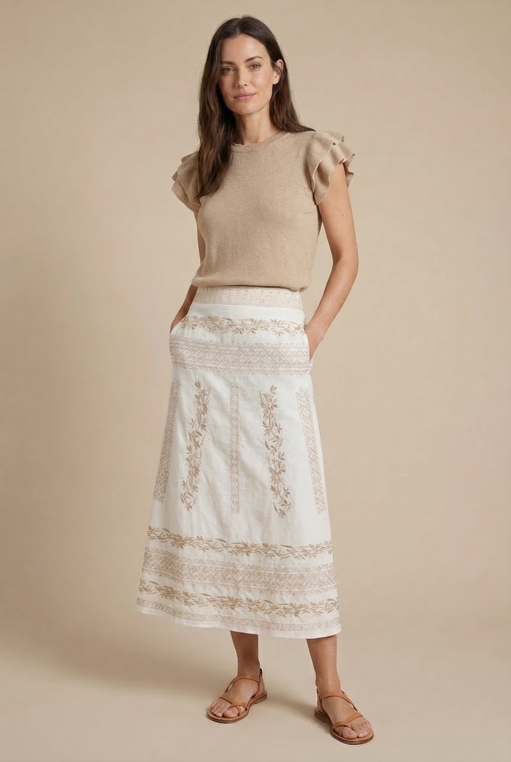 Falda blanca de mujer con bordado beige, estilo primavera, combinada con top beige y sandalias.