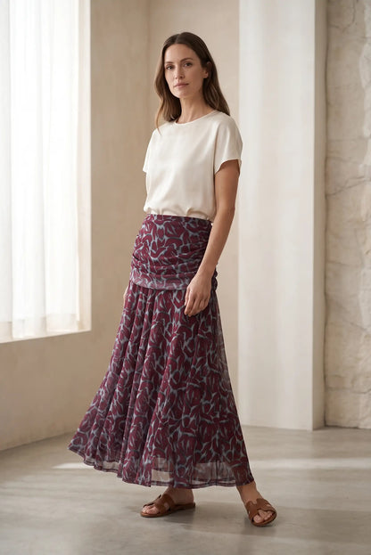 Mujer con camiseta blanca y falda larga estampada en tonos granate y gris