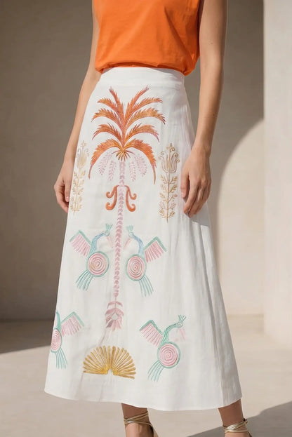 Falda blanca midi con bordados tropicales coloridos, ideal para primavera o verano.