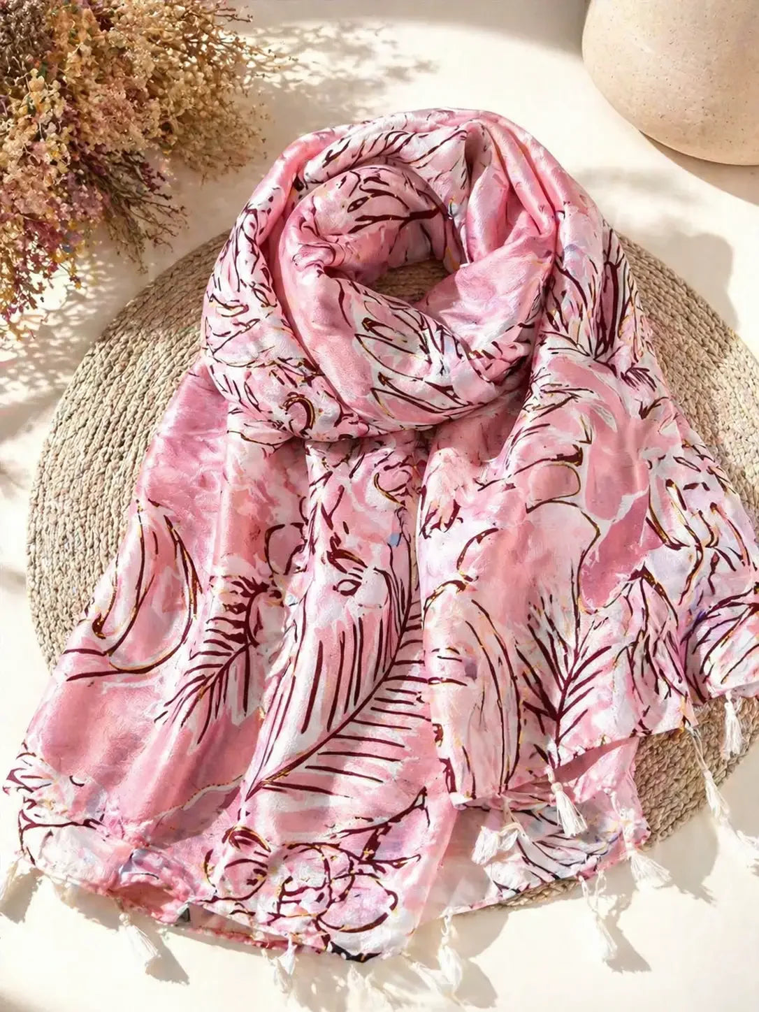 Bufanda rosa con estampado de hojas tropicales y flecos, ideal para looks casuales y estilosos