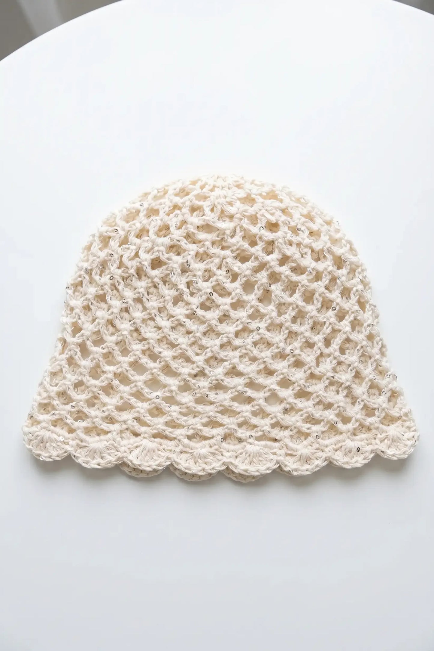 Gorro tejido en crochet beige con detalles brillantes y borde ondulado, ideal para moda femenina