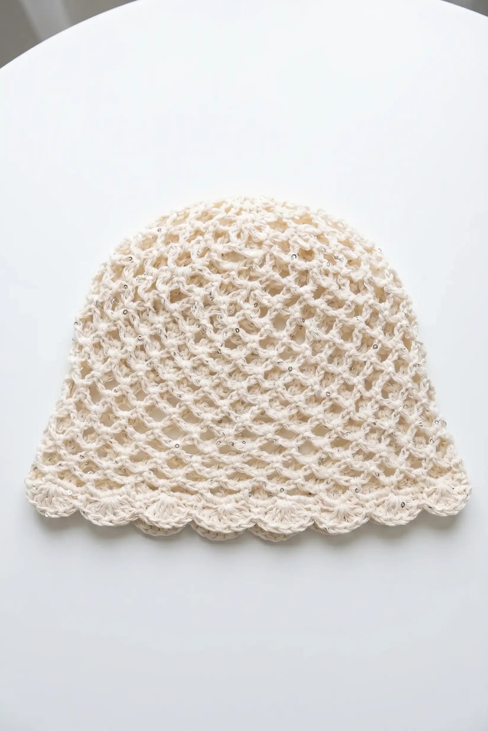 Gorro tejido en crochet beige con detalles brillantes y borde ondulado, ideal para moda femenina