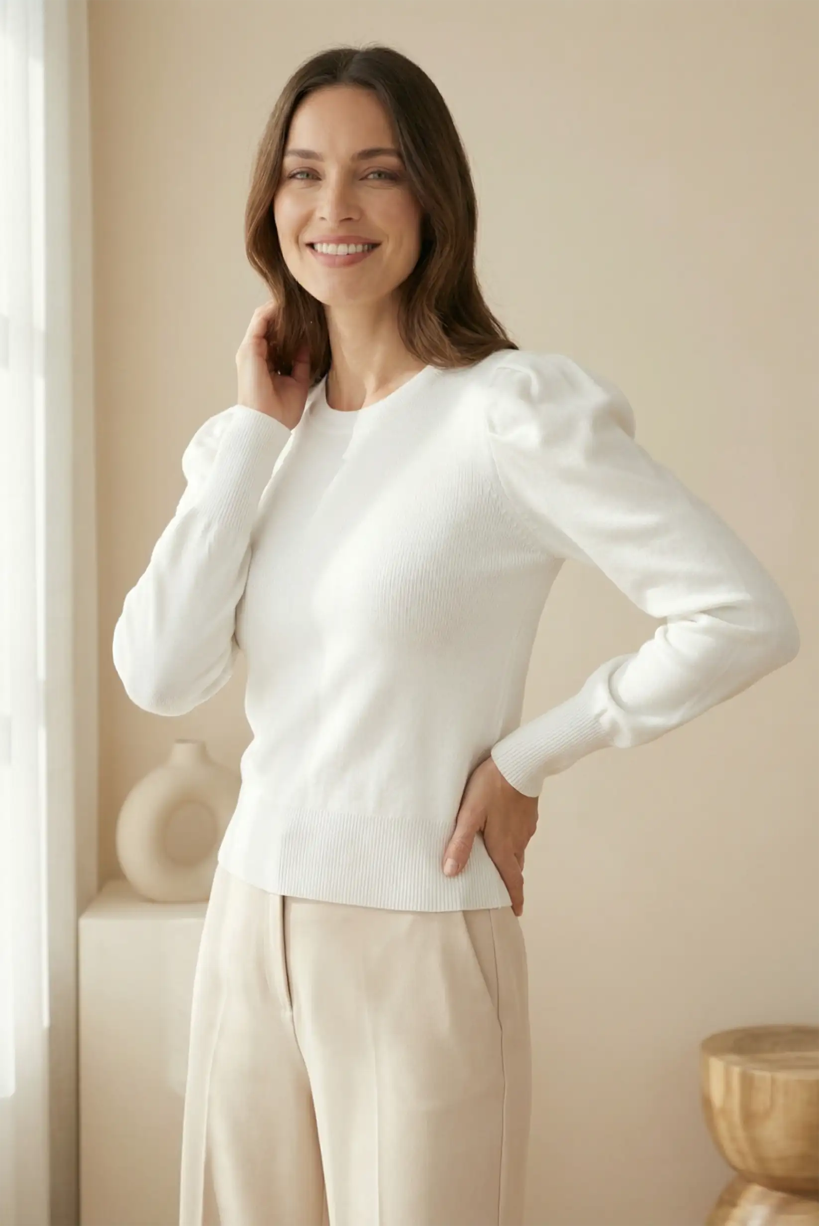 Mujer con jersey blanco de manga larga y pantalón beige, moda casual CHICA del Sur.