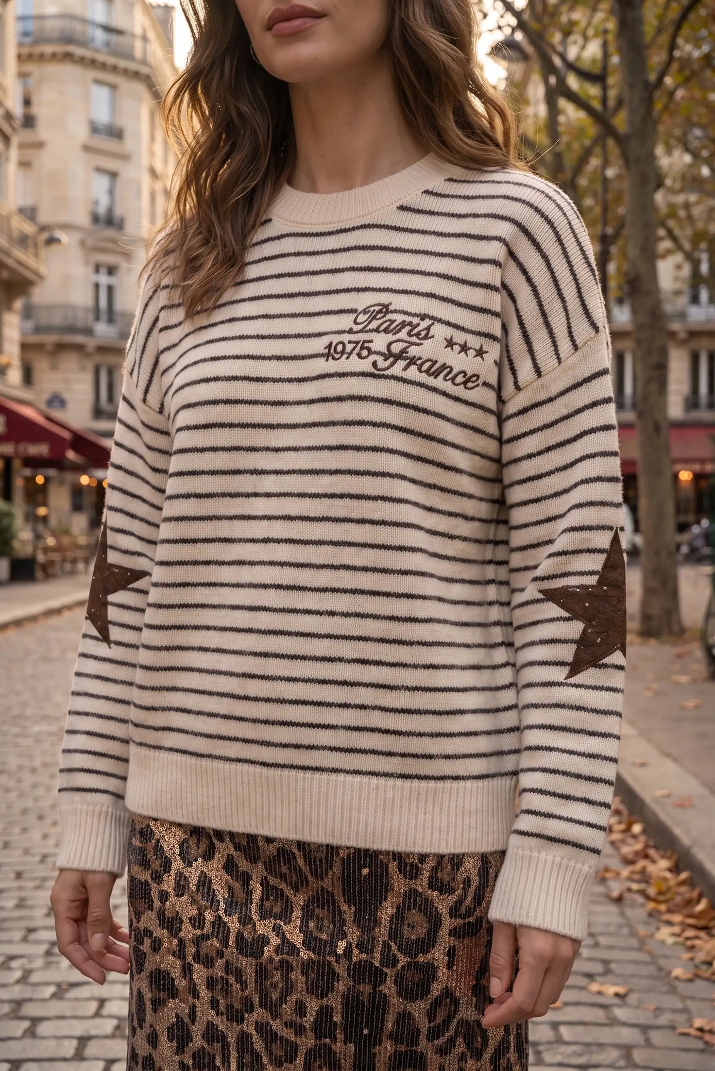 Mujer con jersey de rayas beige y negro con texto de París y falda de leopardo brillante