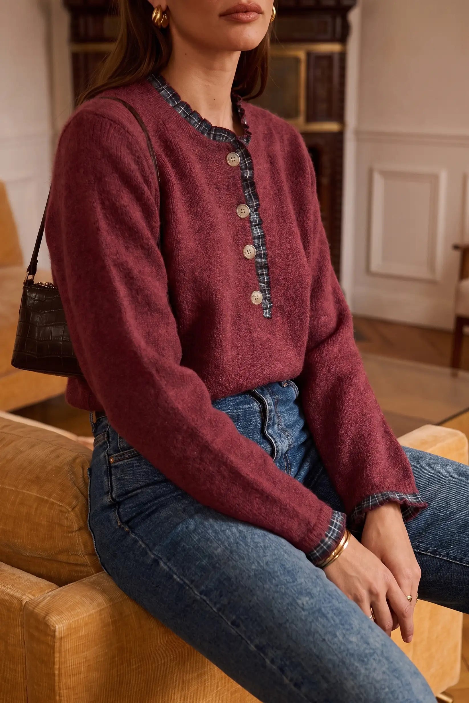 Suéter rojo vino con botones y detalles a cuadros, combinado con jeans azules y bolso negro