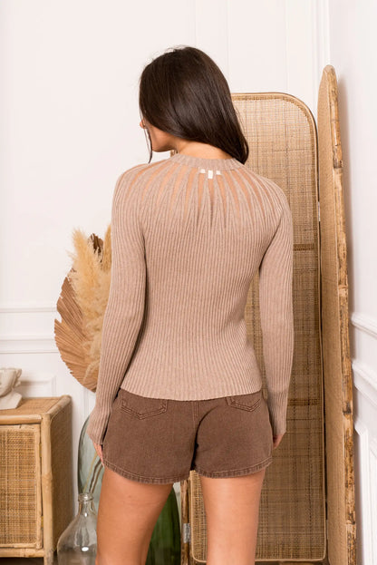 Mujer de espaldas con jersey de punto taupe de manga larga y shorts marrones en ambiente acogedor