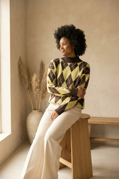 Mujer con jersey de rombos amarillo y marrón sentada en taburete de madera en interior minimalista